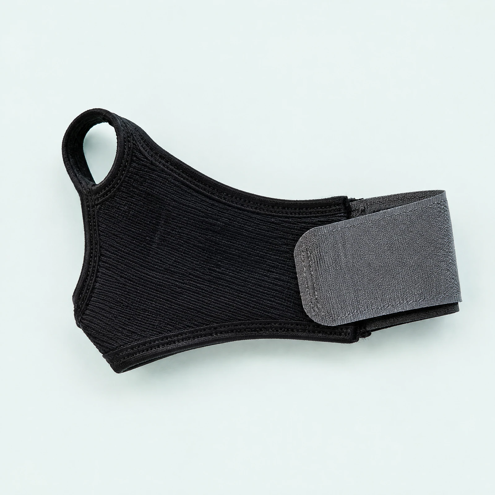 Black ribbed-knit wrist support wrap with gray hook-and-loop strap and thumb loop