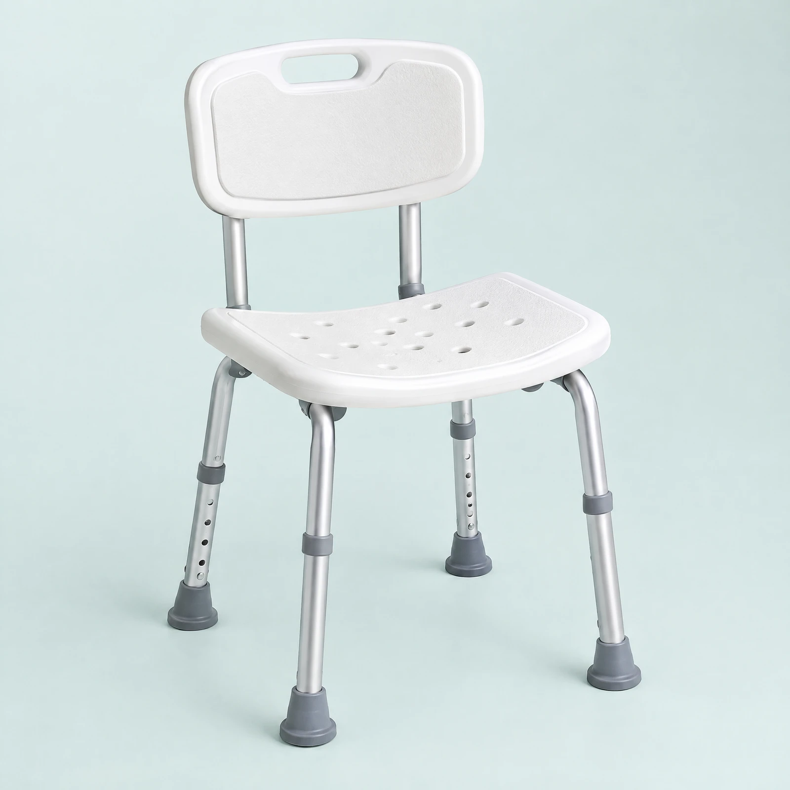 White shower chair with curved backrest, holes in the seat and silver-tone legs